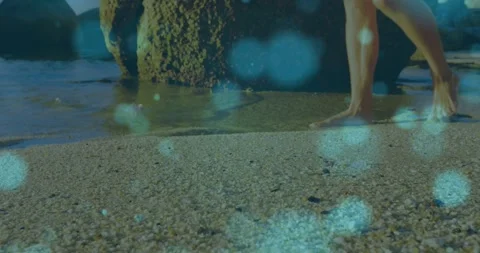 Man shifting weight and walking shore, testing water, teal-blue bokeh overlaying 動画素材 330161234