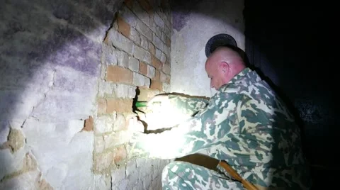 Man shines a flashlight through the hole in the wall Video stock 58452267
