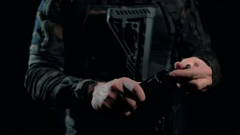 Man shirt on a black background loads cartridges into the AK magazine 動画素材 144072404