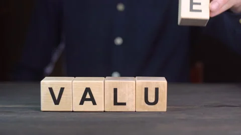 A man in a shirt composes the word VALUE from wooden cubes, close up. Video stock 149874007
