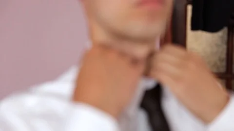 Man in shirt dressing up and adjusting tie on neck at home. Is going to work. Stockbeeldmateriaal 123701865