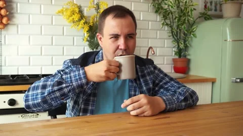 Man in a shirt is drinking tea while sitting at the table in the kitchen. moscow Stock Footage 161391997