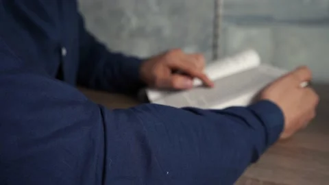 Man in a shirt is reading a book at a table Stock Footage 154056642