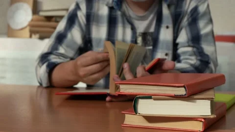 Man in a shirt is reading a book while sitting at a table Stock Footage 159756072