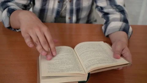 A man in a shirt reads a book while sitting at the table. Stock-Footage 157712642