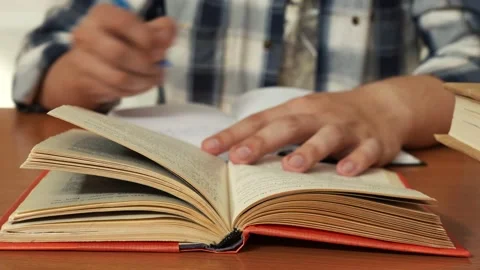 Man in a shirt takes notes in a notebook from a book 스톡 동영상 157712954