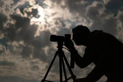 Man shooting the night cloudy sky under moon with a tripod Stock Photos