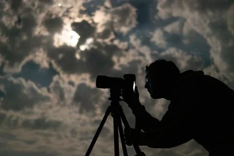 Man shooting the night cloudy sky under moon with a tripod Stock Photos