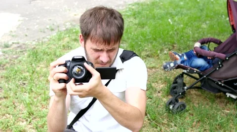 Man shooting with photo camera while his child sleeping in buggy Stock Footage 50548625