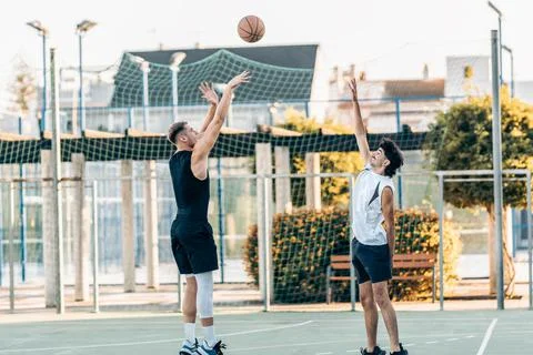 Man shooting a three-pointer during a basketball match between friends outdoors Stock Photos