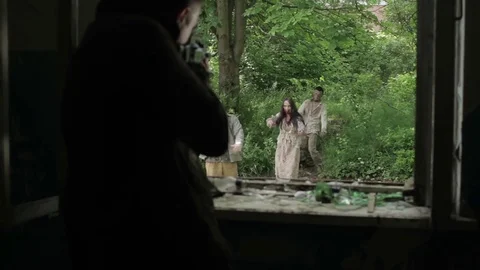 A man shoots zombies from the window of an abandoned house. Stock Footage 77491252