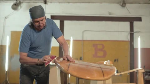 Man in the shop grinds the side of the surf Board Stock Footage 133492931