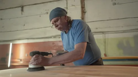 Man in the shop grinds the surface of the surf Board Stock Footage 132943974