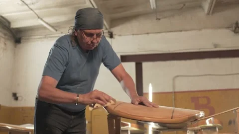 Man in the shop grinds the surface of the surf Board Stock Footage 132981504