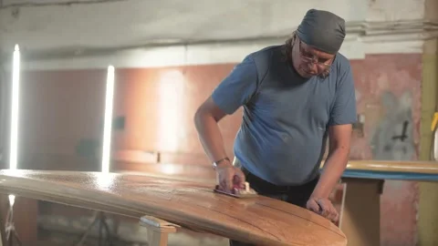 Man in the shop grinds the surface of the surf Board Stock Footage 132981579