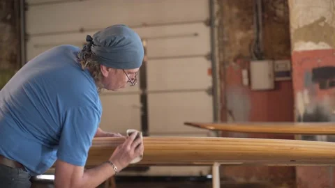 Man in the shop grinds the surface of the surf Board Stock Footage 132981580