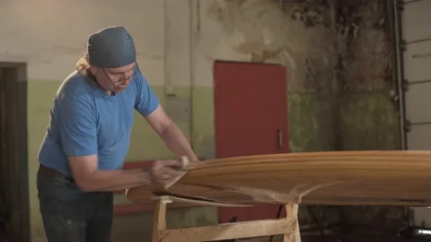 Man in the shop grinds the surface of the surf Board Stock Footage 132981612