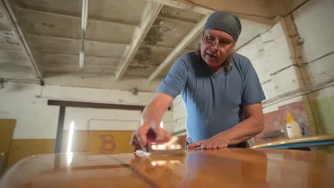 Man in the shop grinds the surface of the surf Board Stock Footage 133022655