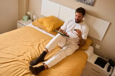 Man shopping online using tablet and credit card in bed Stock Photos