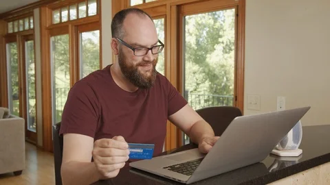 Man shops online using credit card and laptop, buying from home with e-commerce Stock Footage 125407623