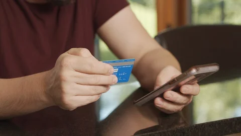 Man shops online using credit card and cell phone, buy from home with e-commerce Stock Footage 127936773