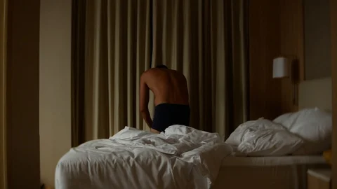 Man in shorts opens the curtains on the window Stock Footage 86462519