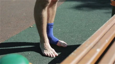 A man in shorts putting on an ankle support. Slow motion Stock Footage 67626610