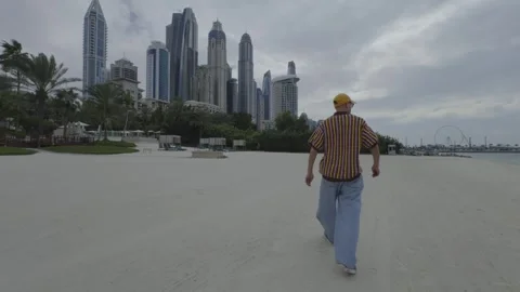 Man, shot from the back, walks against the backdrop of high-rise buildings Stock Footage 273490553