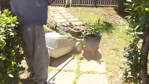 MAN SHOT FROM BEHIND WHILE CUTTING GRASS Video stock 243593541