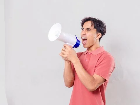 Man shouting into a megaphone with an angry expression while looking to the.. Stock Photos