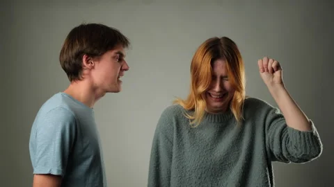 Man Shouting at Woman While She Signals for Help on Gray Background Stock Footage 257493615