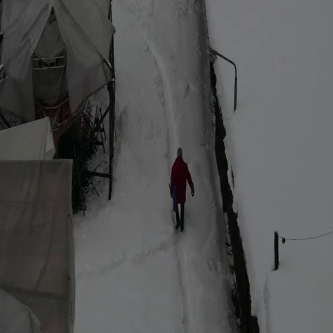 Man with a shovel walking in a small path walkway in a snowy day Stock Footage 69557931