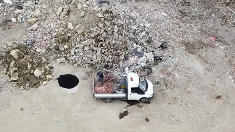 Man Shoveling Red Bricks Off the Back of a Work Truck in a Construction Yard Stock Footage 186841326
