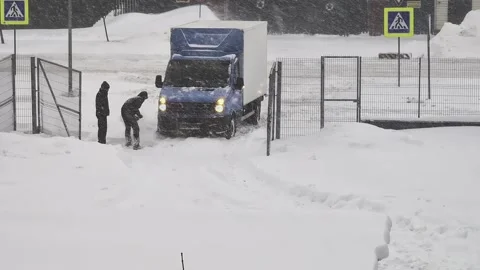 Man shoveling snow to clear path for delivery truck struggling during heavy Stock Footage 326750024
