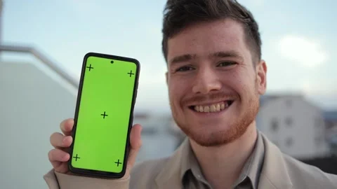 Man showcasing the capabilities of his smartphone while standing on a balcony at Stock Footage 241287727