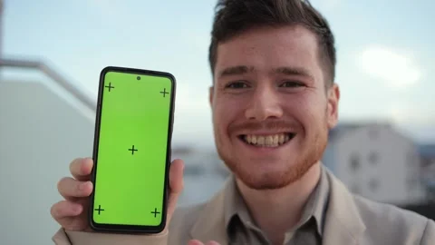 Man showcasing the capabilities of his smartphone while standing on a balcony at Stock Footage 307355045