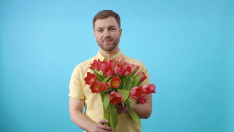 Man showing bunch of red tulips in his hand on blue background Stock-Footage 266450744