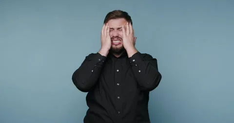 Man showing emotions while standing in front of a blue background with hand.. Vidéo 326790275