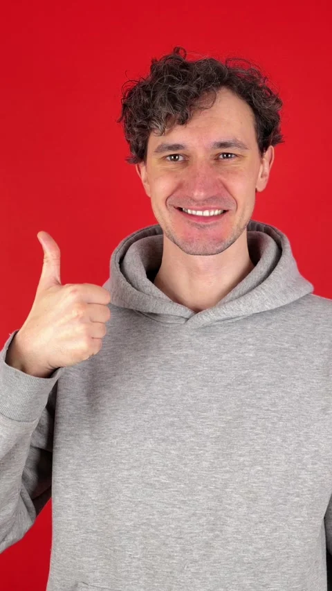 Man showing in front thumb up hand sign like gesture, looking smiling at camera. 動画素材 304761253