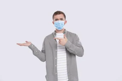 Man Showing Hand to Side Pointing at It. Man Wearing Medical Mask. Gesture Foto stock