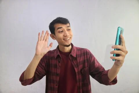 A man showing happy expression when waving hand during video call Stock Photos