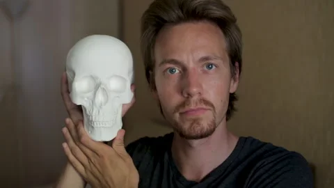 Man showing human skull replica to camera, concept of anatomy, halloween, death Stock Footage 292652591