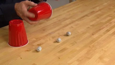 Man showing magic tricks with cups and aluminum balls Stock Footage 99056095