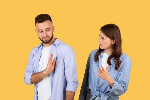 Man showing stop gesture to arguing woman, yellow background Stock Photos