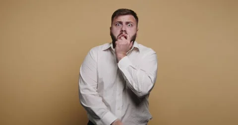 Man showing surprise in a studio with a plain background while touching his.. Vídeo Stock 326797795