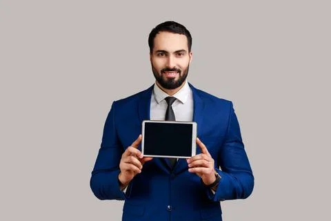 Man showing tablet empty screen for adv, has happy facial expression, looking at Stock Photos