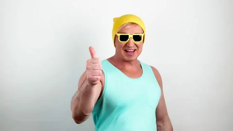 Man showing thumb up, winner Yes in yellow beanie, blue tank top. Excited guy Stock Footage 235850737