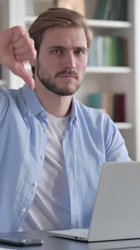 Man Showing Thumbs Down Sign While using Laptop at Work, Vertical Video Stock Footage 339578942