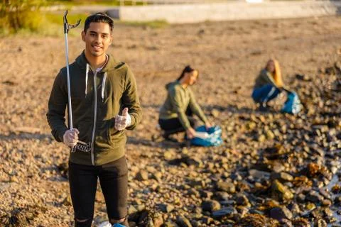 Man showing thumbs up with environment protector volunteers at beach Stock Photos