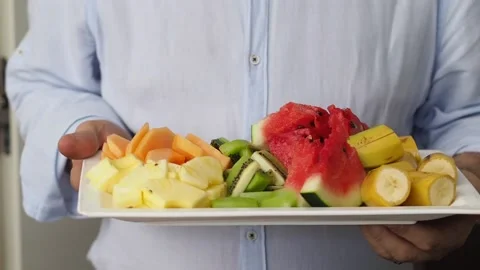 A man showing a tray of fresh fruit (ananas, kiwi, melon, watermelon, Stock Footage 149069213